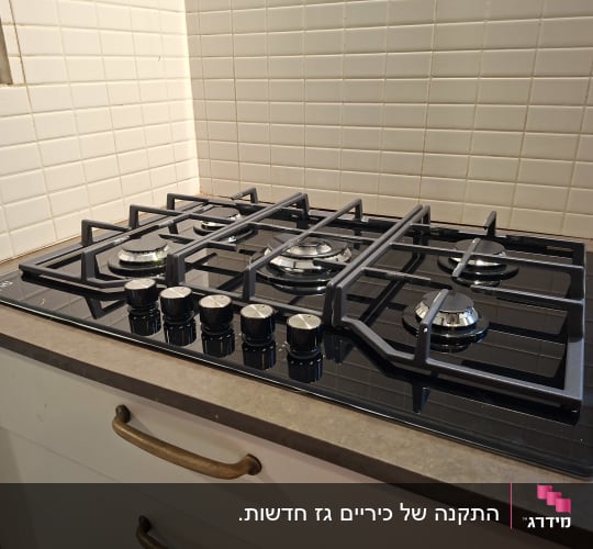 כיריים גז על משטח מטבח עם אריחי קיר לבנים